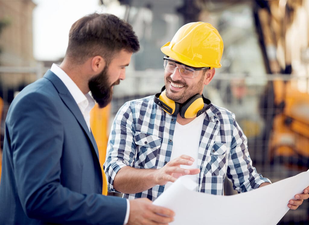 Business Insurance - Cheerful Contractor Discussing Building Blueprints with a Businessman on a Commercial Jobsite